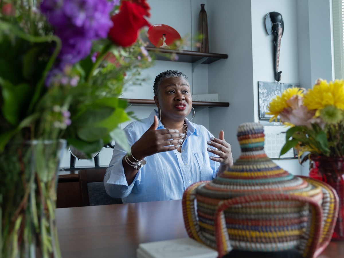 TaShun Bowden-Lewis, Connecticut's chief public defender, makes a hand gesture while sitting at a table in her office, speaking to a reporter in close distance.