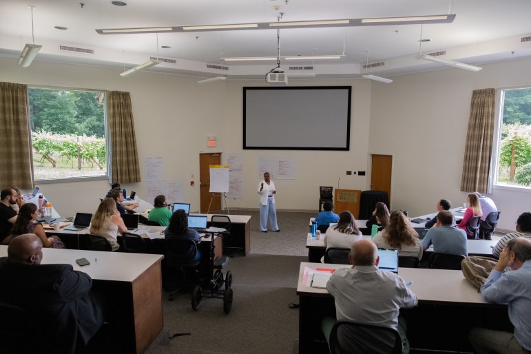 TaShun Bowden-Lewis, Connecticut's chief public defender, is standing at the front of a room, making a hand gesture, and talking to a group of people during a public defender training session.