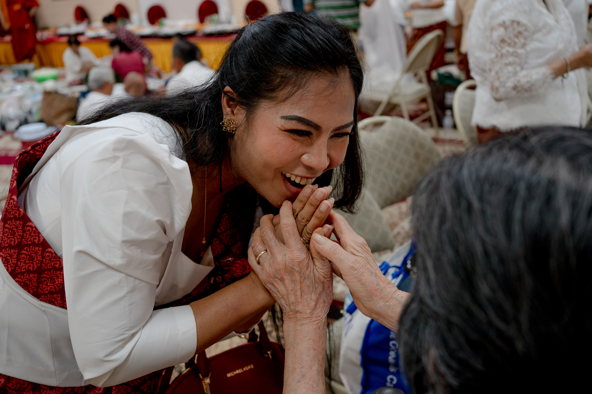Dany Khan smiles with her hands in a prayer position. Cheav Peak grasps her hands.