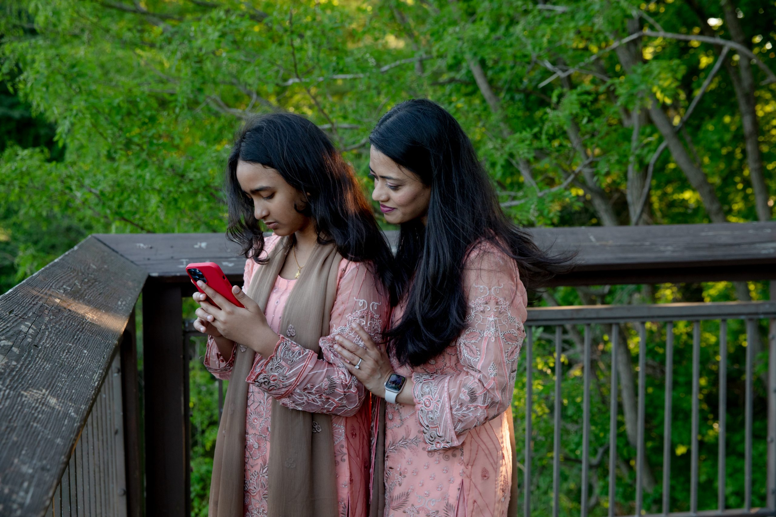 One woman looks at a cell phone as nother