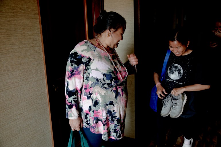 Aiti Rai and Pabi Maya Rai smiling. Aiti holds a pair of sneakers.
