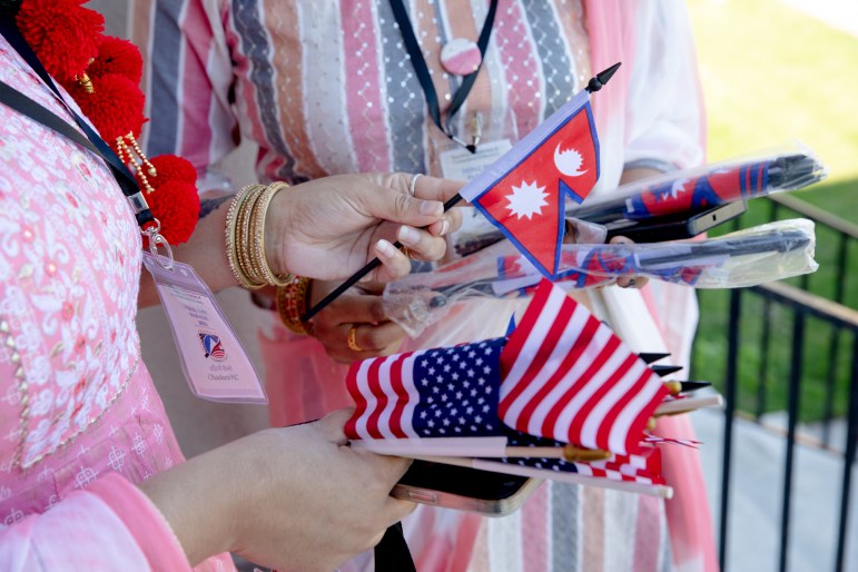 Two women's hands are holding miniature flags.