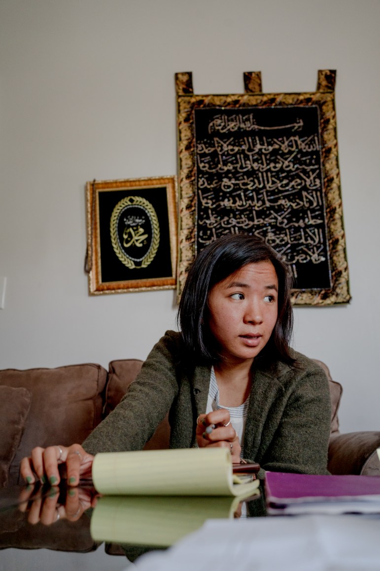 Aiti Rai sits on a couch with a legal pad in front of her on a table. She's speaking to someone on her left.