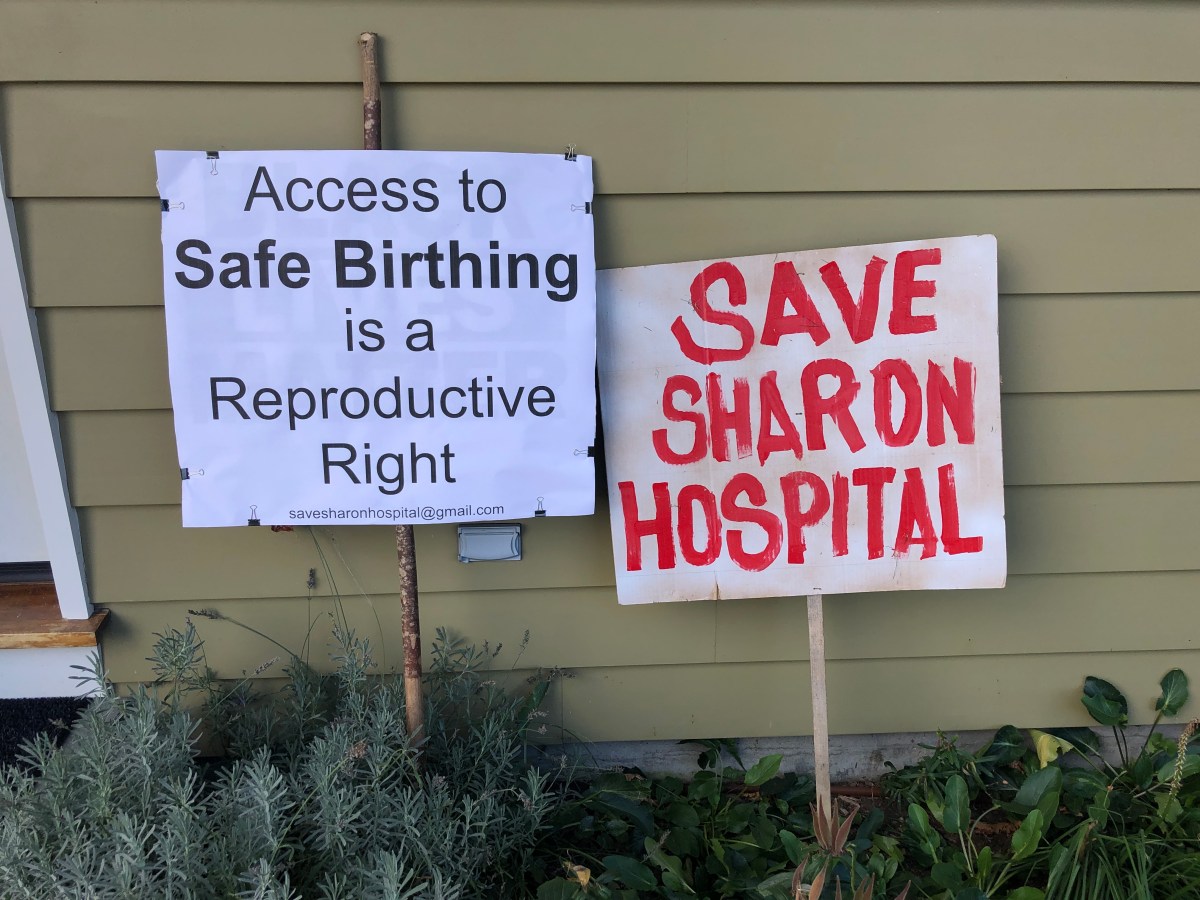 Two picket signs lean against the outside of a building.