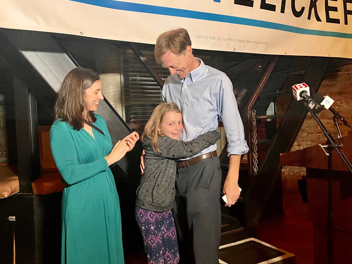 Mayor Justin Elicker gets a hug from his daughter while his wife claps and smiles nearby.