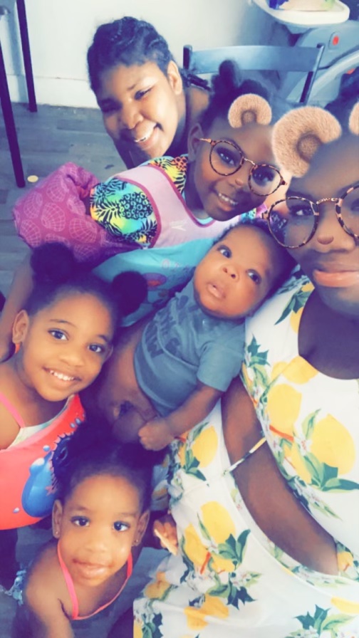 A woman holding a baby poses with her son and four daughters. The Snapchat filter gives some of them bear ears and noses.