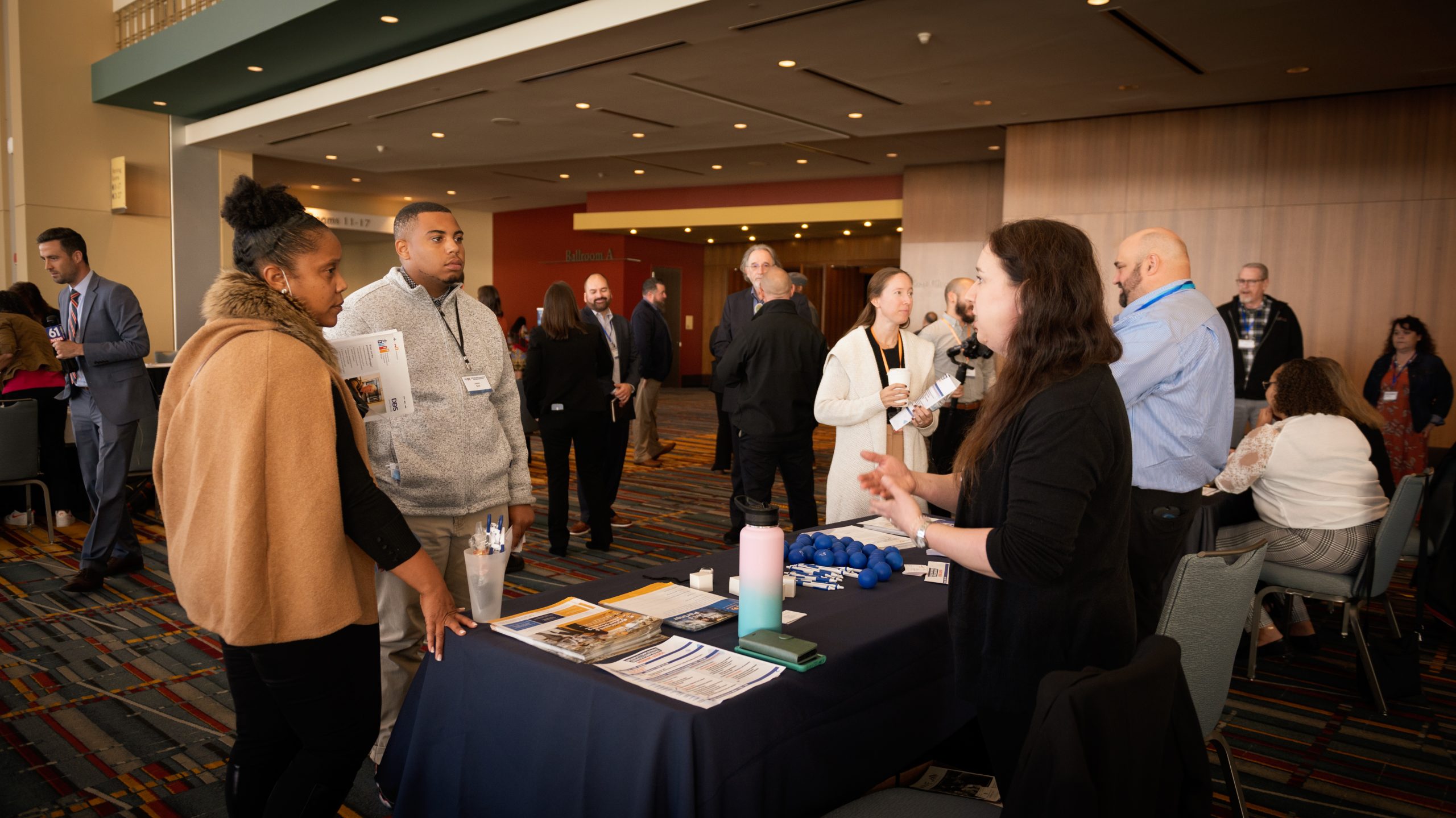People standing and talking at information tables at a conference.