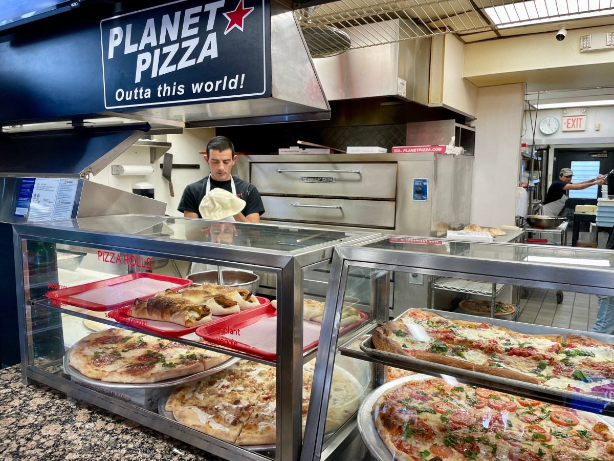 A pizza maker stretches dough.