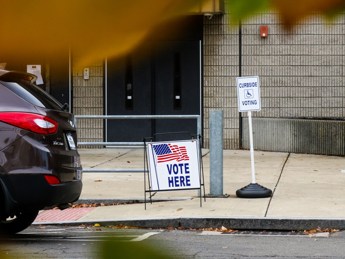 Two signs, one that says "Vote Here" and another that says "Curbside Voting," stand in front of Bridgeport's Paul Lawrence Dunbar School.