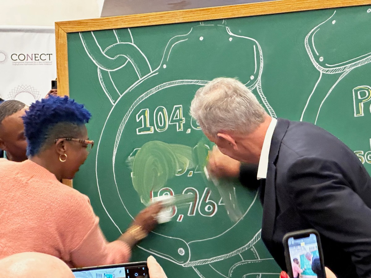 Connecticut Gov. Ned Lamont is standing at a chalkboard with Tammy King. Both are erasing numbers off of a chalkboard as a nod to Connecticut's "clean slate" law, which automatically erases misdemeanors and low-level felonies from the criminal records of some people.