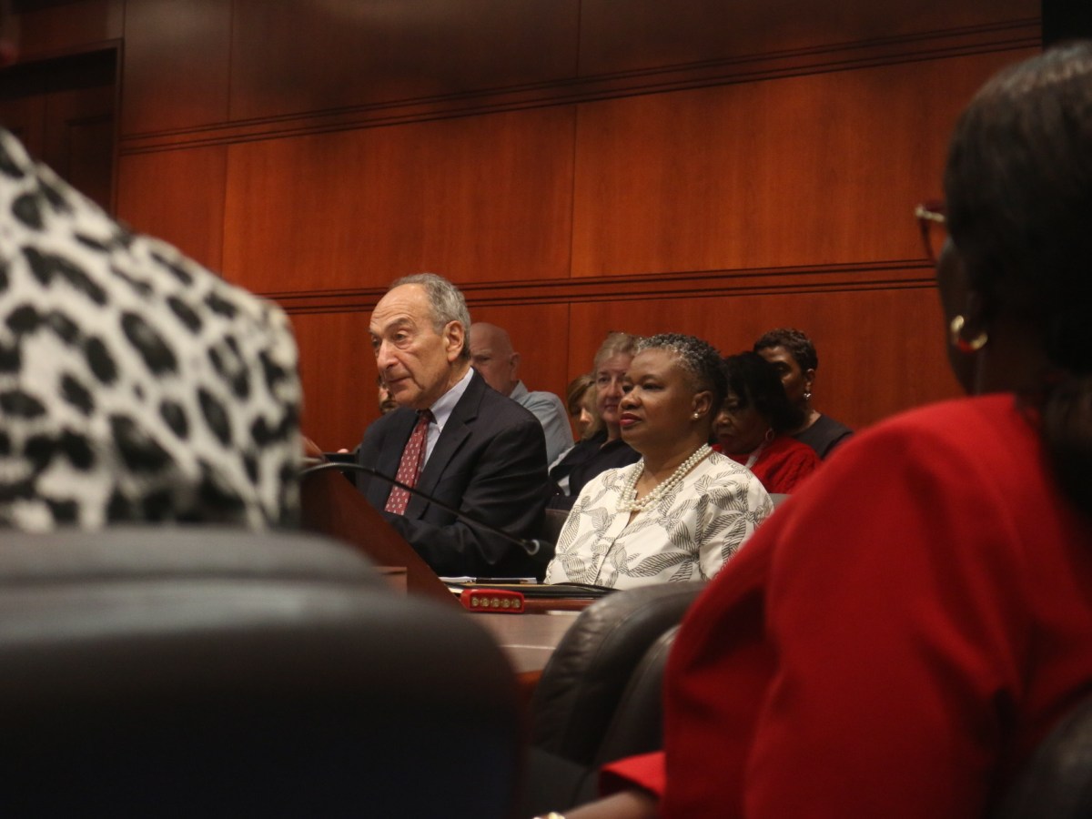 TaShun Bowden-Lewis is sitting next to her attorney, Thomas Bucci, as people are seen looking at them from a distance.