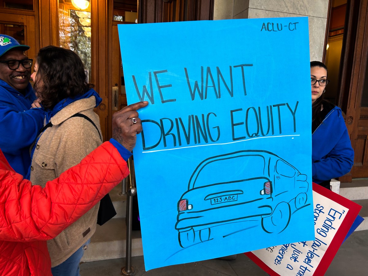 A blue sign that says "we want driving equity" with an illustration of a vehicle.