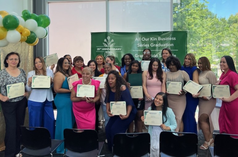 Women hold certificates and pose for a photo at a graduation ceremony.