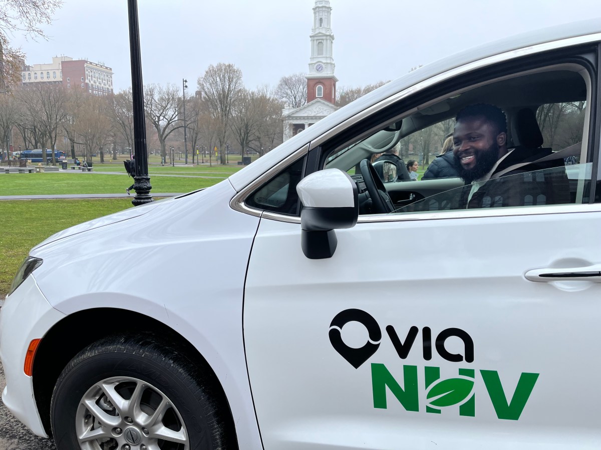 A driver sits in a white Chrysler van with a decal reading "Via NHV."